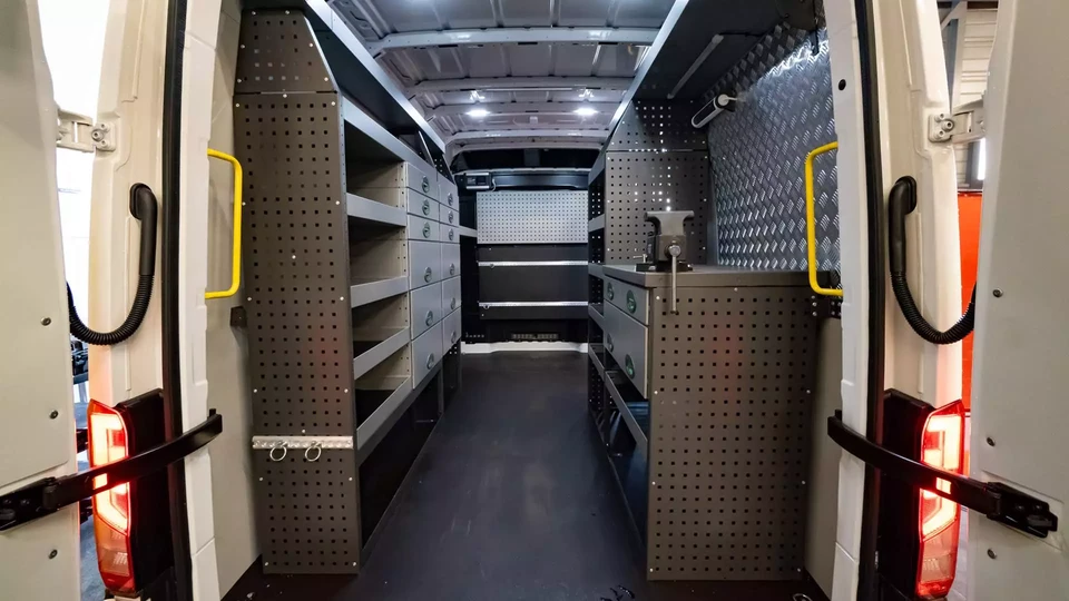 Atelier de maintenance de véhicules industriels avec mécanicien en combinaison de service travaillant sur un camion gris