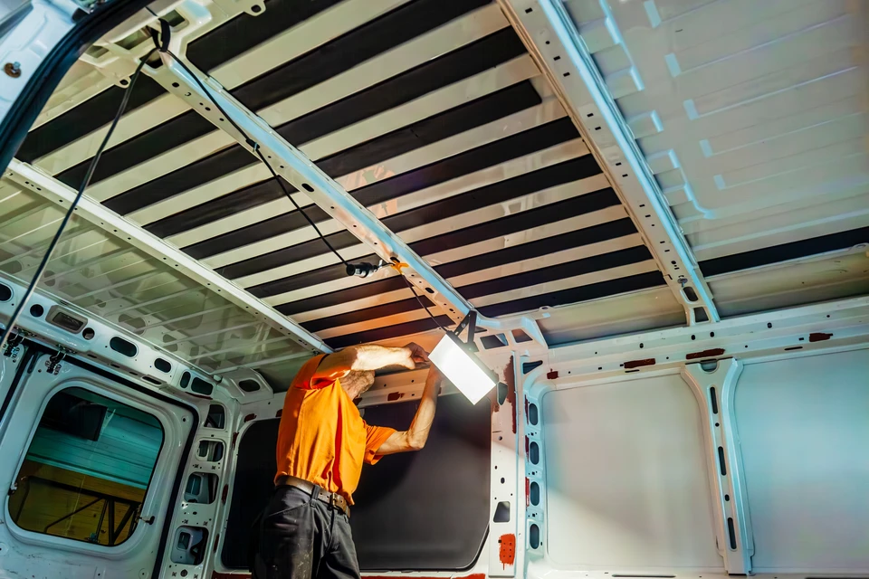 Un homme en tenue professionnelle examine attentivement l'intérieur d'un véhicule dans un environnement de concession automobile